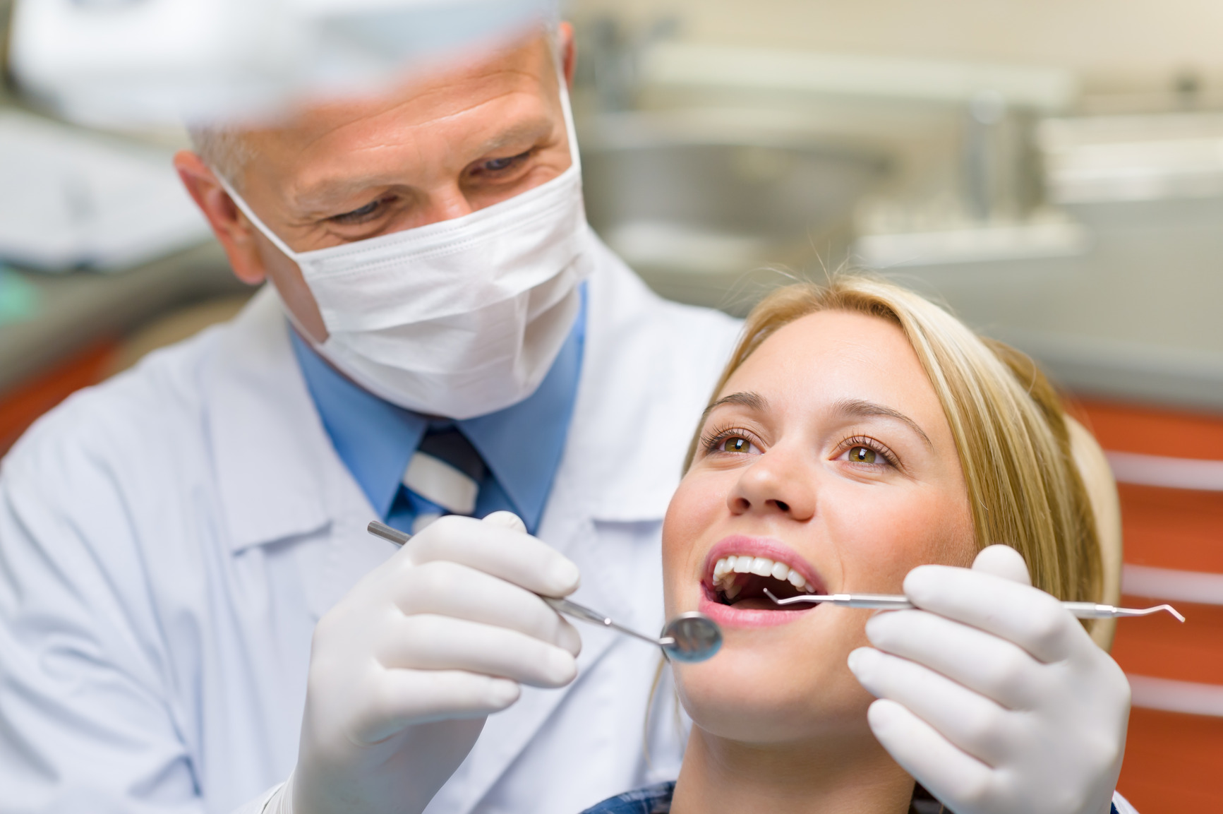 A dentist is examining the teeth of a woman.